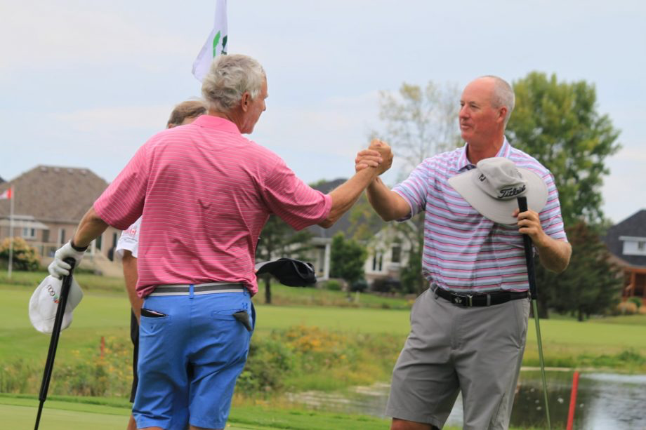 two men shaking hands on golf course