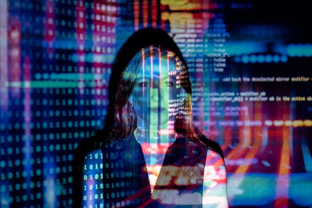 A double exposure image of a woman's face merged with a background of digital data and computer code.