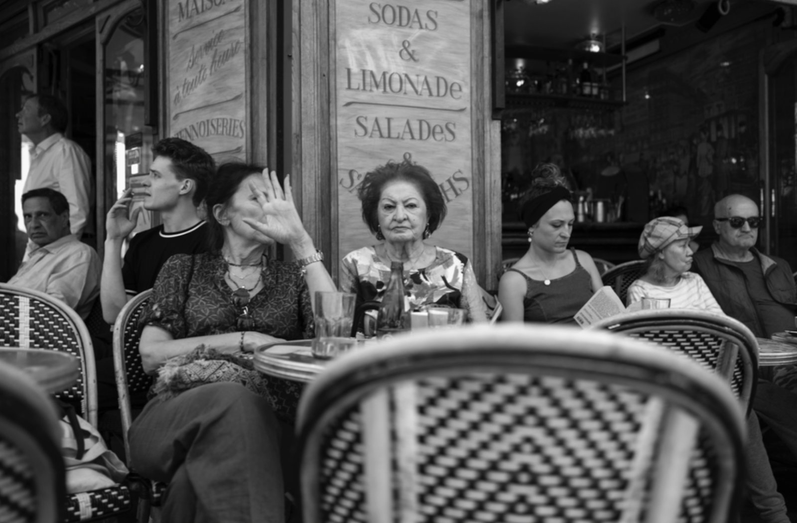 A black and white image of Italian locals, sitting in front of a cafe, chatting and interacting with each other.