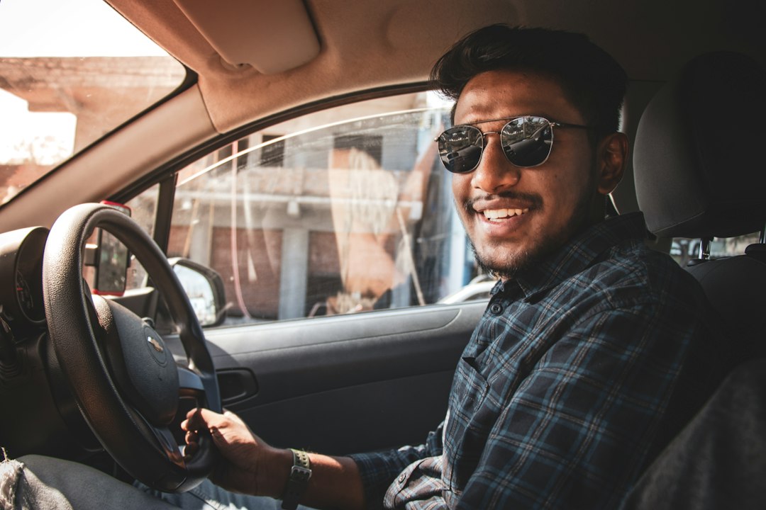 A person with sunglasses behind the wheel of a car 
