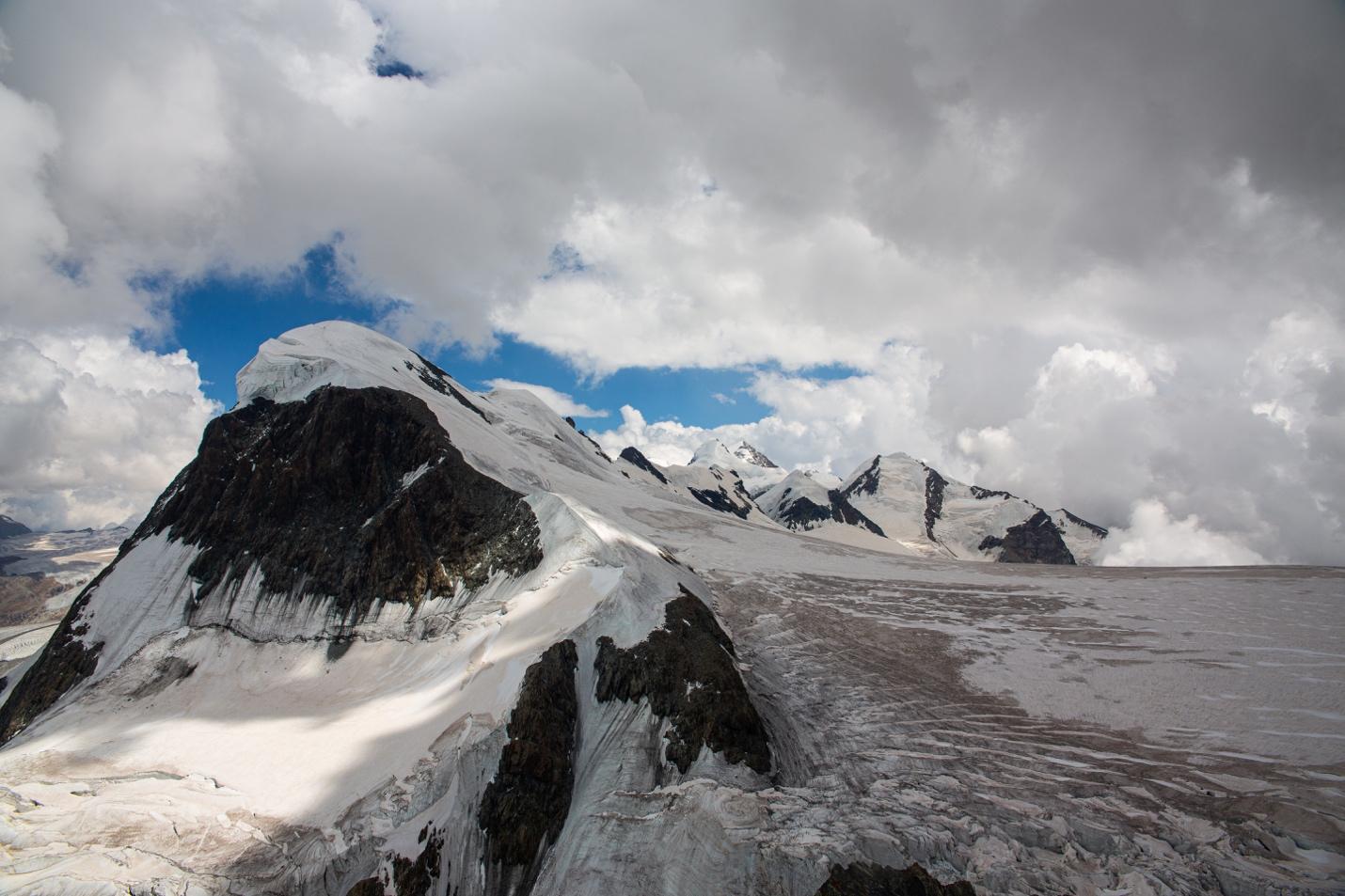 A snowy mountain with clouds in the sky

Description automatically generated