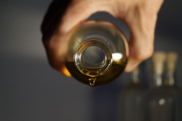 Hand holding a glass jar of ayurvedic hydrating oil being poured out