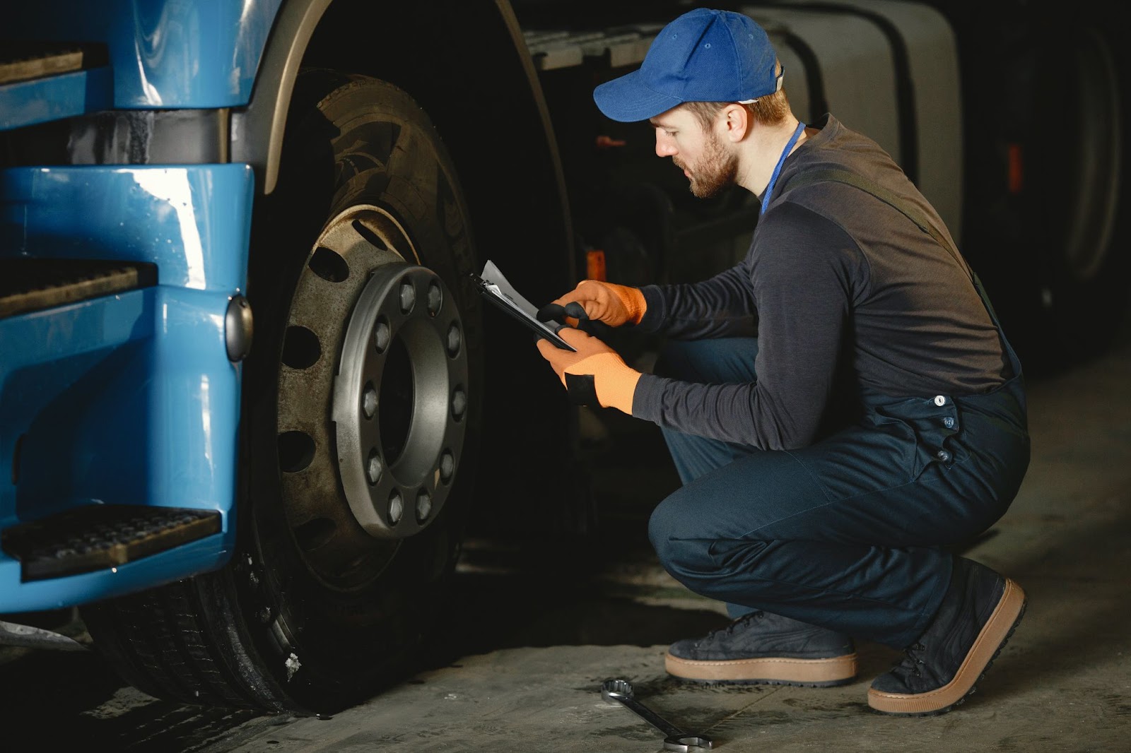 A mechanic kneeling down and checking on a semi-truck tire