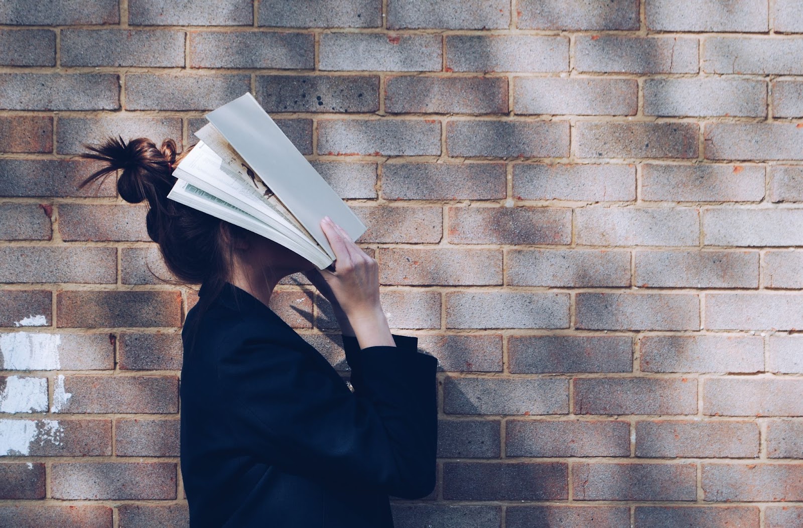 woman hiding herself behind a book