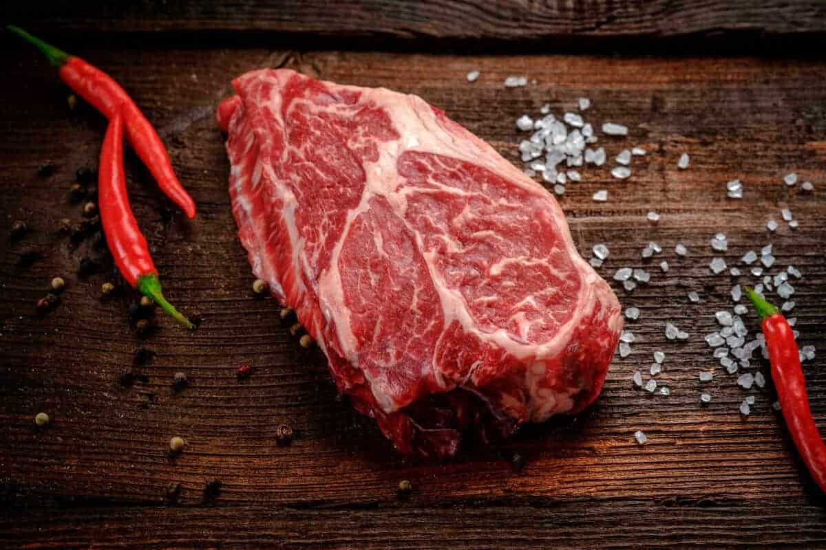 Friptură crudă pe o masă de tocat cu chilis roșu