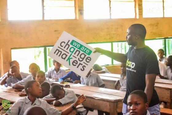 A person holding a sign in a classroom

Description automatically generated