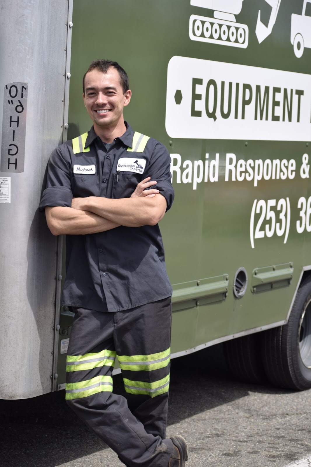 An Equipment Experts, Inc. employee, Michael, standing with arms crossed against an truck trailer