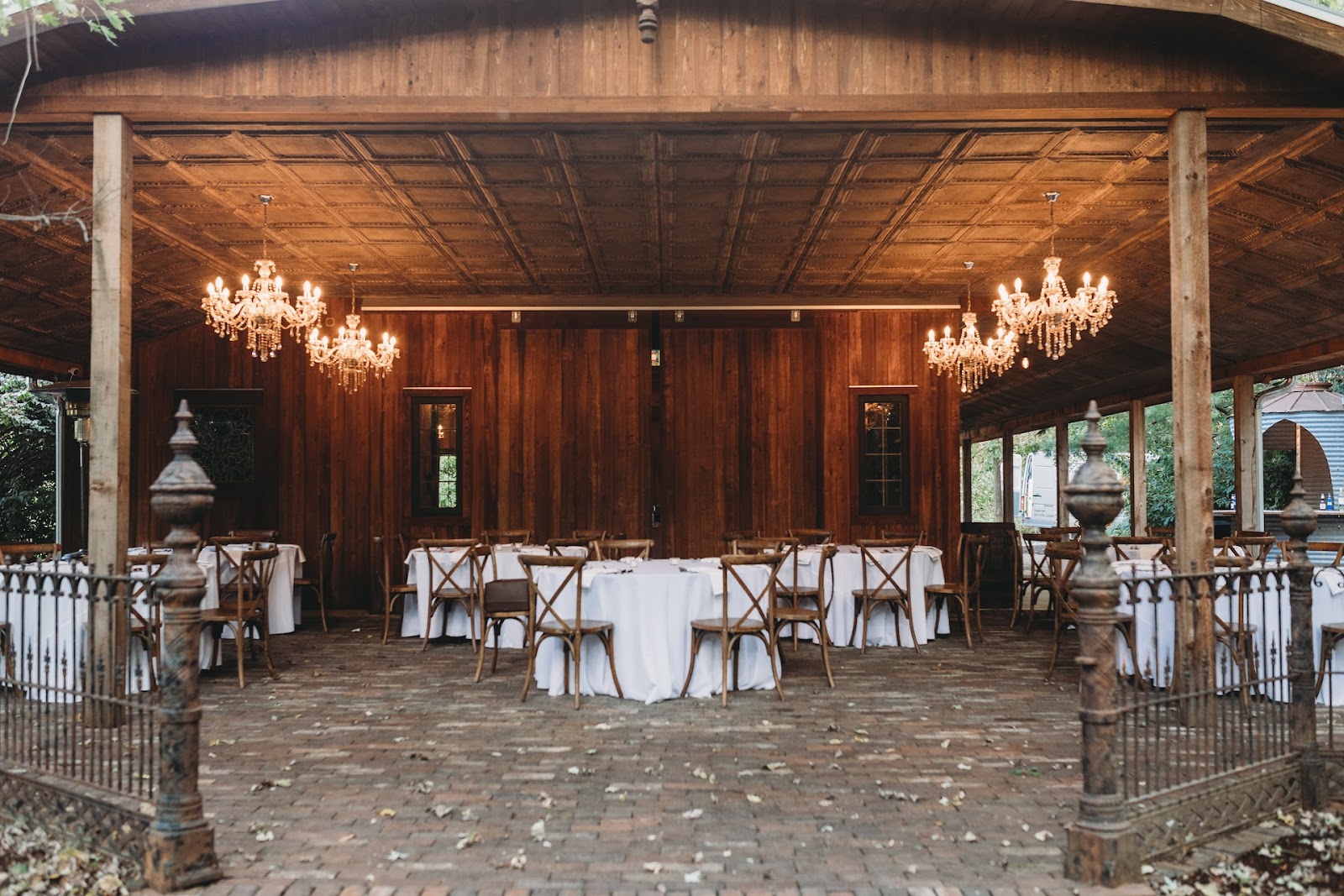 A rustic wedding reception area with white tables and chandeliers, ready for wedding messages to a couple