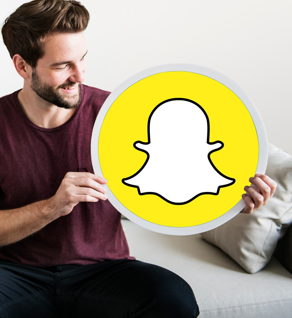 A cheerful man holding a Snapchat icon. 