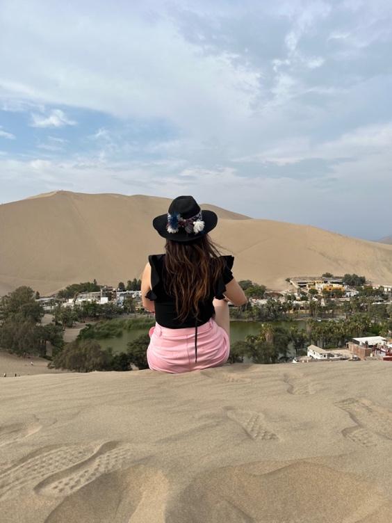 A person sitting on a sand dune

Description automatically generated