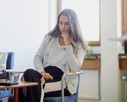person sitting on a couch in a therapist's office, looking thoughtful