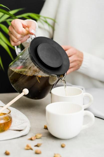 Woman pouring tea in cup from tea brewer