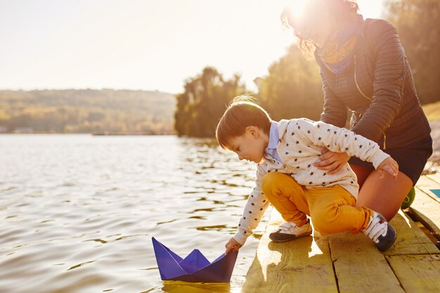 Mother and Son Putting a Paper Boat in a Lake