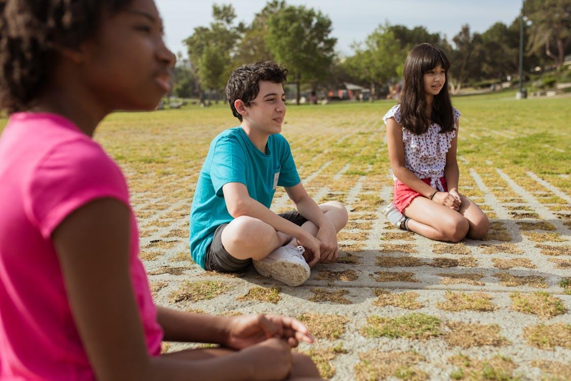 Free Children Sitting on Green Field Stock Photo