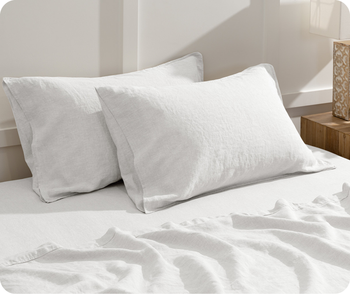 Our White Vintage Washed European Linen Pillowcases shown on a bed with coordinating linen flat sheet and fitted sheet.