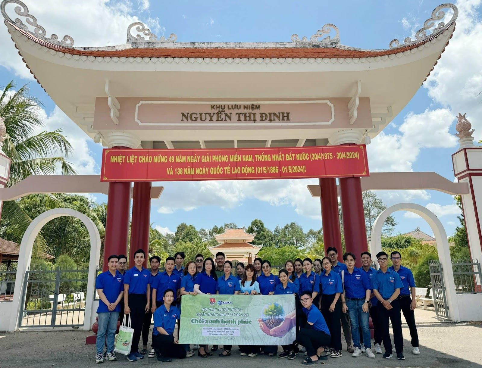 A group of people posing for a photo under a red and white archwayDescription automatically generated