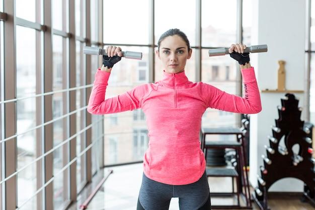 Free photo woman holding dumbbells with hands up