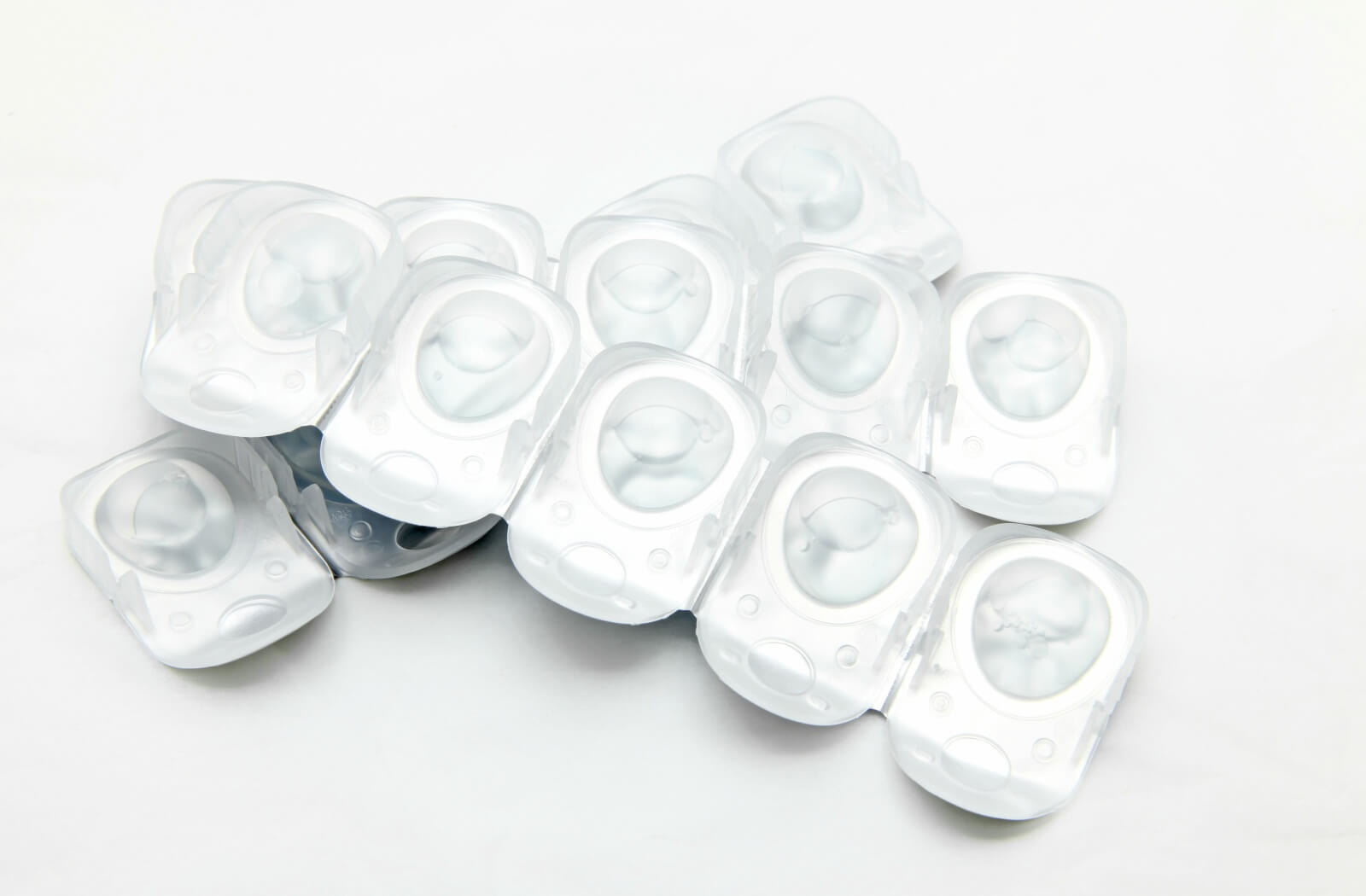 A stack of sealed plastic containers of disposable contact lenses against a white backdrop.