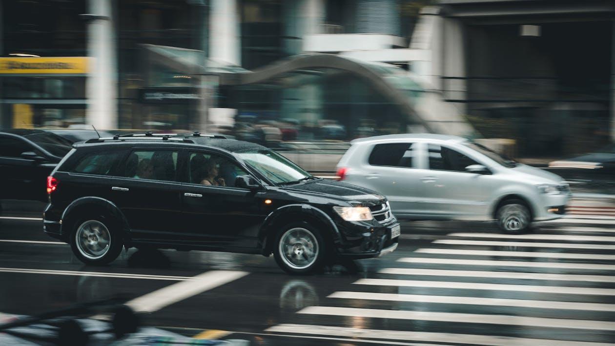 Free Black Suv Beside Grey Auv Crossing the Pedestrian Line during Daytime Stock Photo