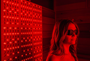 A person wearing sunglasses and standing in front of a wall with red lights

Description automatically generated