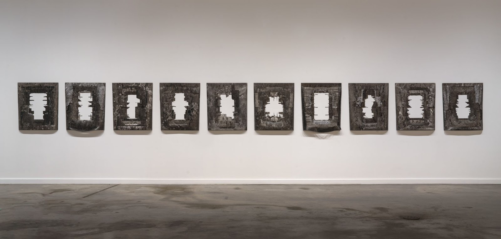 Image: Installation view, Yoonmi Nam, Generally Meant to be Discarded. The negative Tyvek® cuts from the Delivered and Discarded series, treated with sumi ink and alcohol based sanitizer are displayed on the wall. Image courtesy of the artist, photo taken by E.G. Schempf