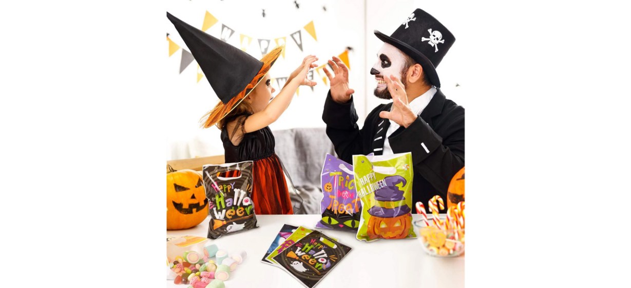 Parent and child in Halloween costumes with Halloween treat bags