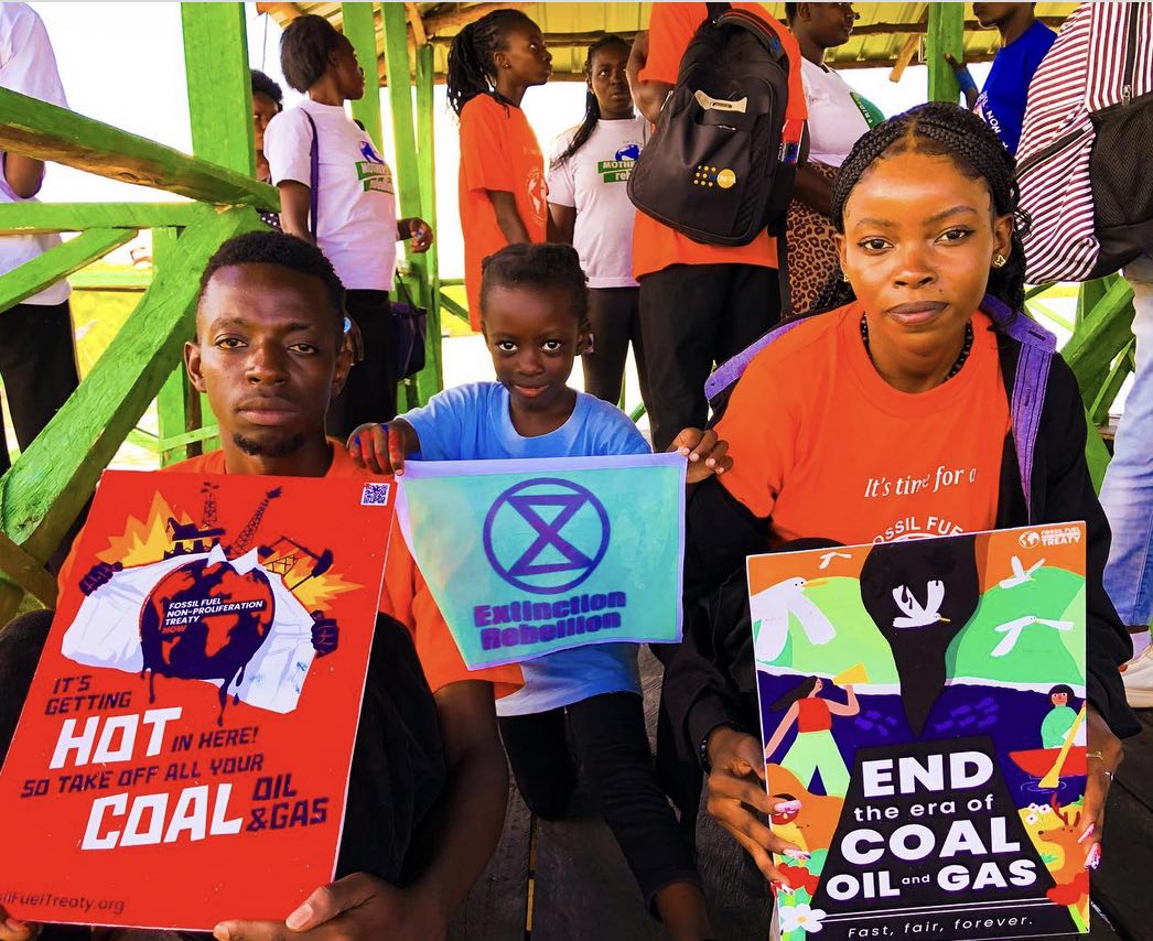 Activists of various ages hold signs of various eco-campaigns and groups, including an XR symbol.