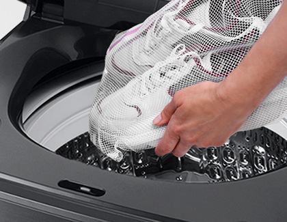 A person putting shoes in a Samsung washing machine.