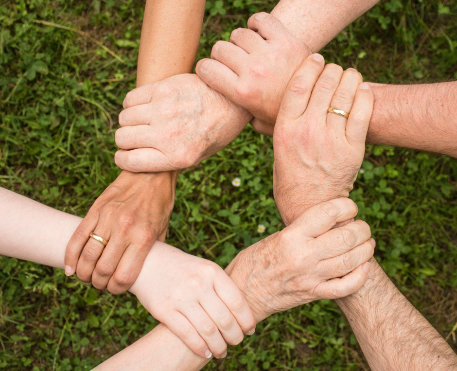 Hands intertwined representing the community that you need to reach your digital wellness and digital decluttering goals. 