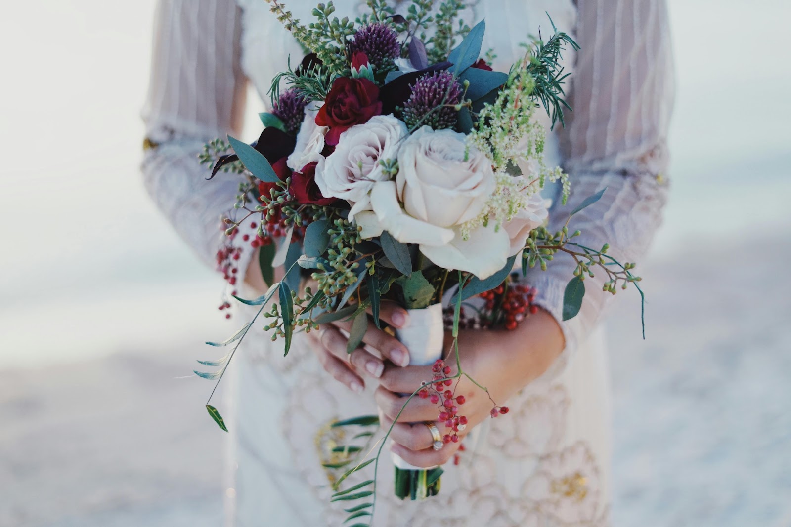 A bride presenting her exquisite flower arrangements as she walks down the beach. 