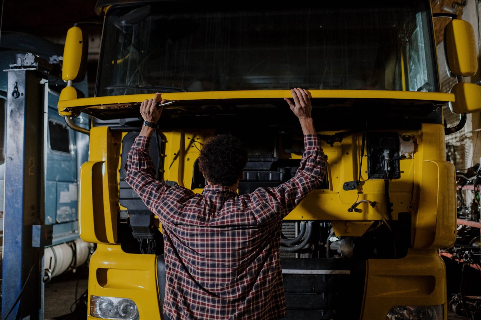 A person opening the hood of a semi truck