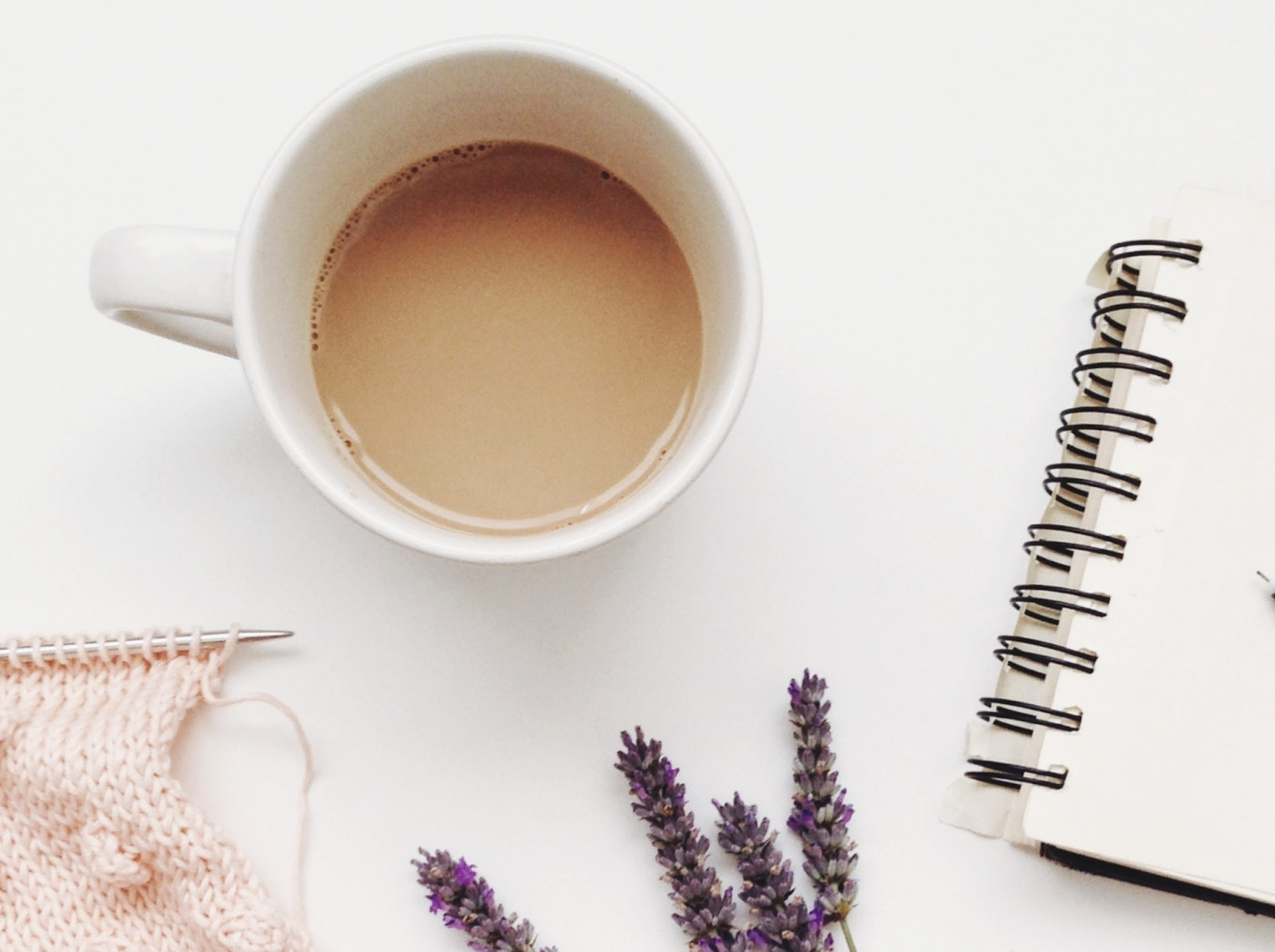 A cup of white coffee on a white surface.