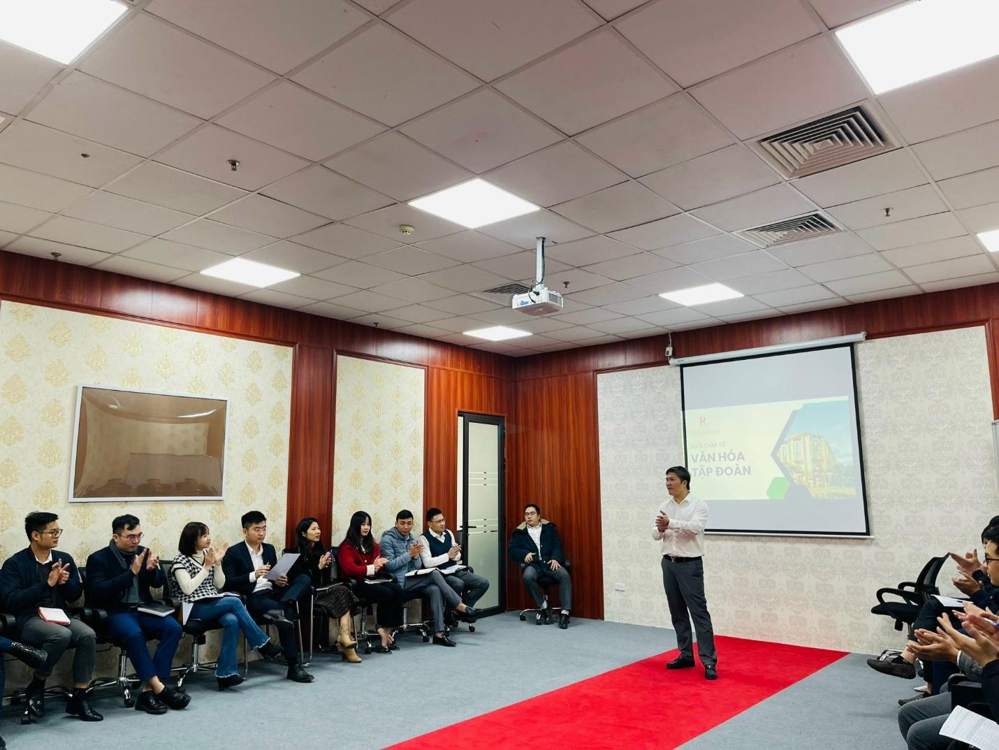 A person standing in front of a group of people sitting in chairs

Description automatically generated