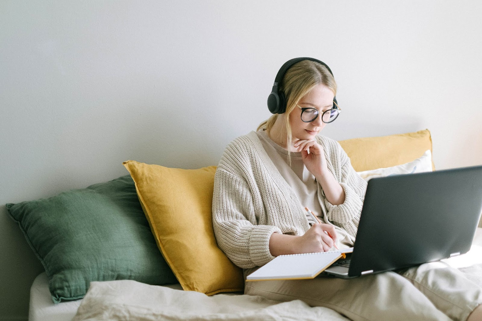 image of woman reflecting on her bed with laptop and notebook