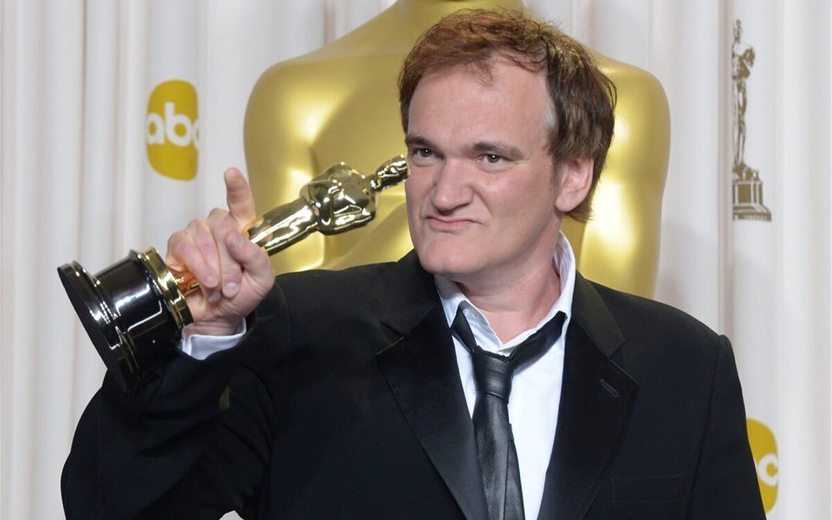 El director Quentin Tarantino posando justo a su estatuilla del premio Oscar.