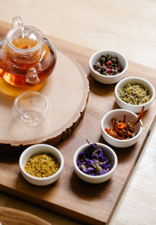 Spices and teas in multiple cups surrounding a pot of tea