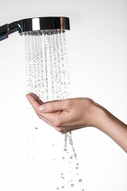 Closeup female hands under the stream of  water from shower - skin care concept