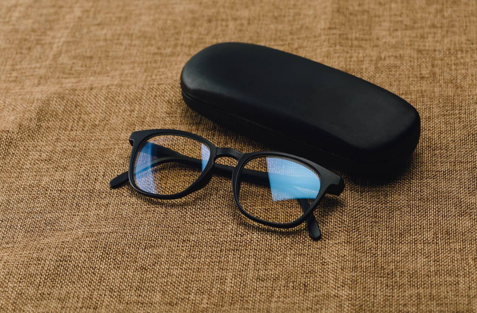 A pair of glasses with UV protection lens coating beside a hard glasses case.