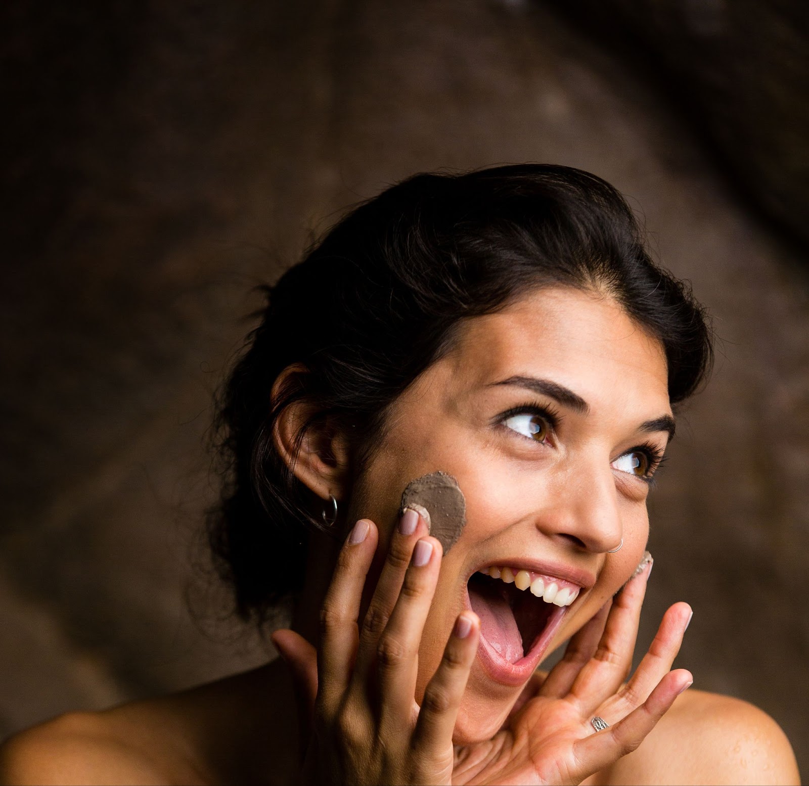 Woman joyfully applying a DIY face mask to her radiant skin