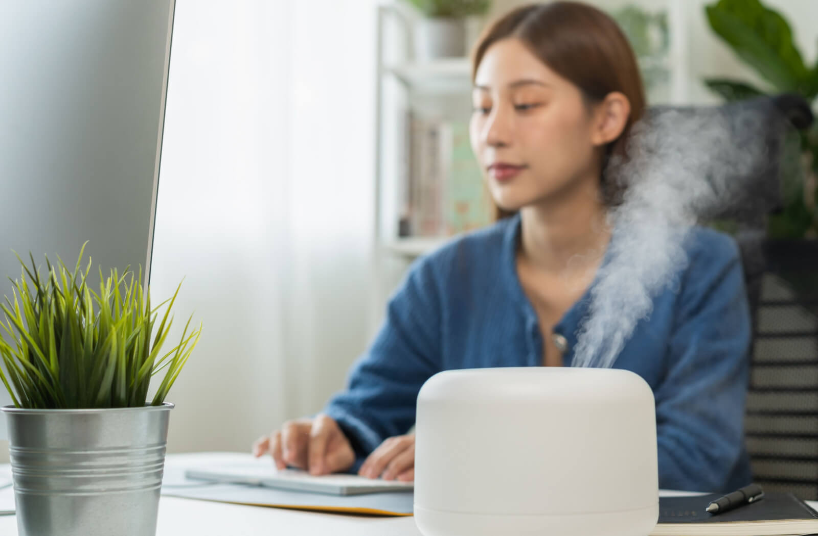 A woman working in her office with a humidifier beside her to prevent dry eyes.