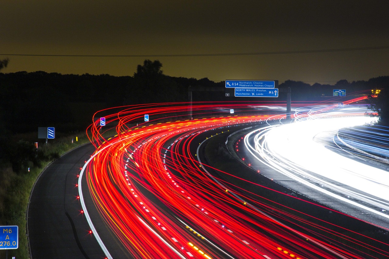Long exposure photo of a highway at night, capturing the dynamic movement of traffic with light trails, illustrating the concept of historical weather data energy planning for optimizing transit and infrastructure.