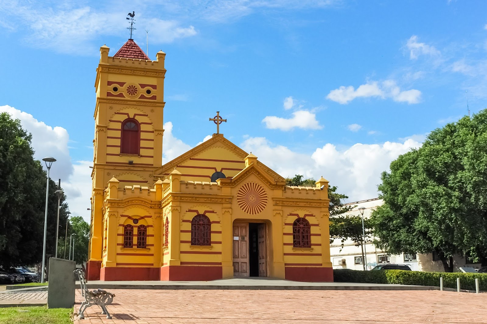 Foto da fachada Igreja Matriz Nossa Senhora do Carmo. Igreja amarela com janelas e detalhes em vermelho, centralizada na praça da cidade