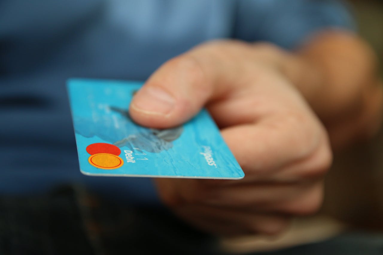 A close-up of a man handing over a blue credit card