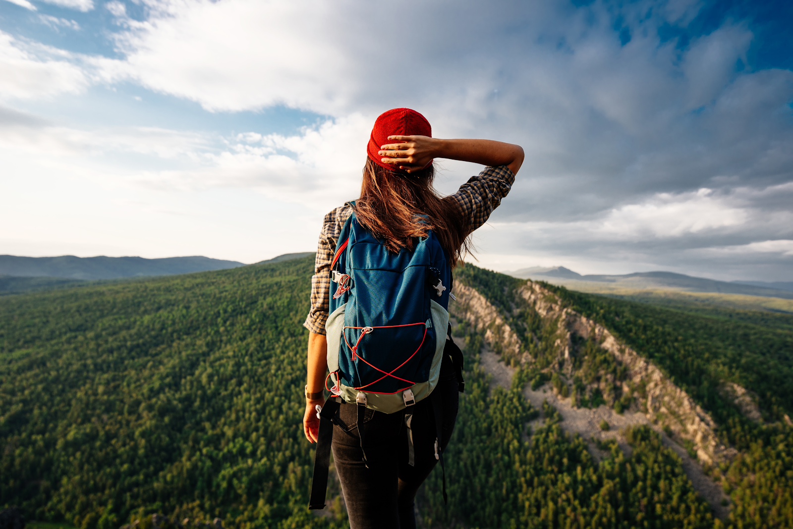 photo of a woman from behind looking at vast mountain range.
