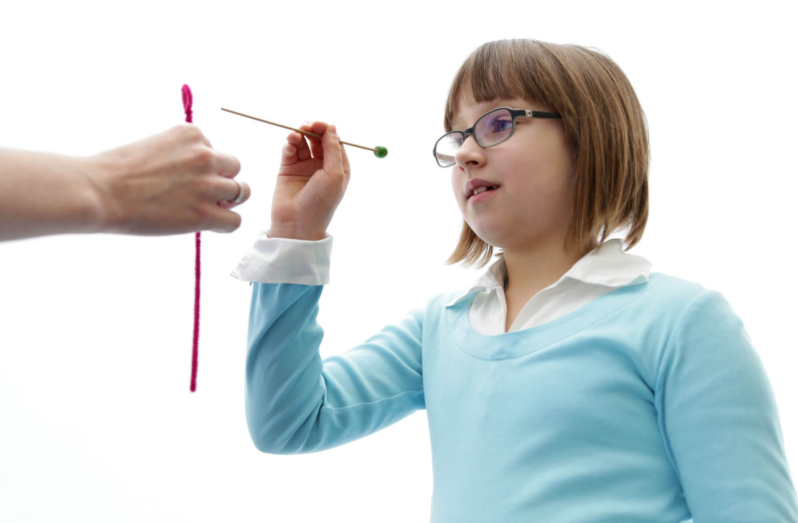 A young girl trying to insert a stick into a small hole during a vision therapy appointment.