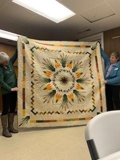 Two women holding a quilt

Description automatically generated