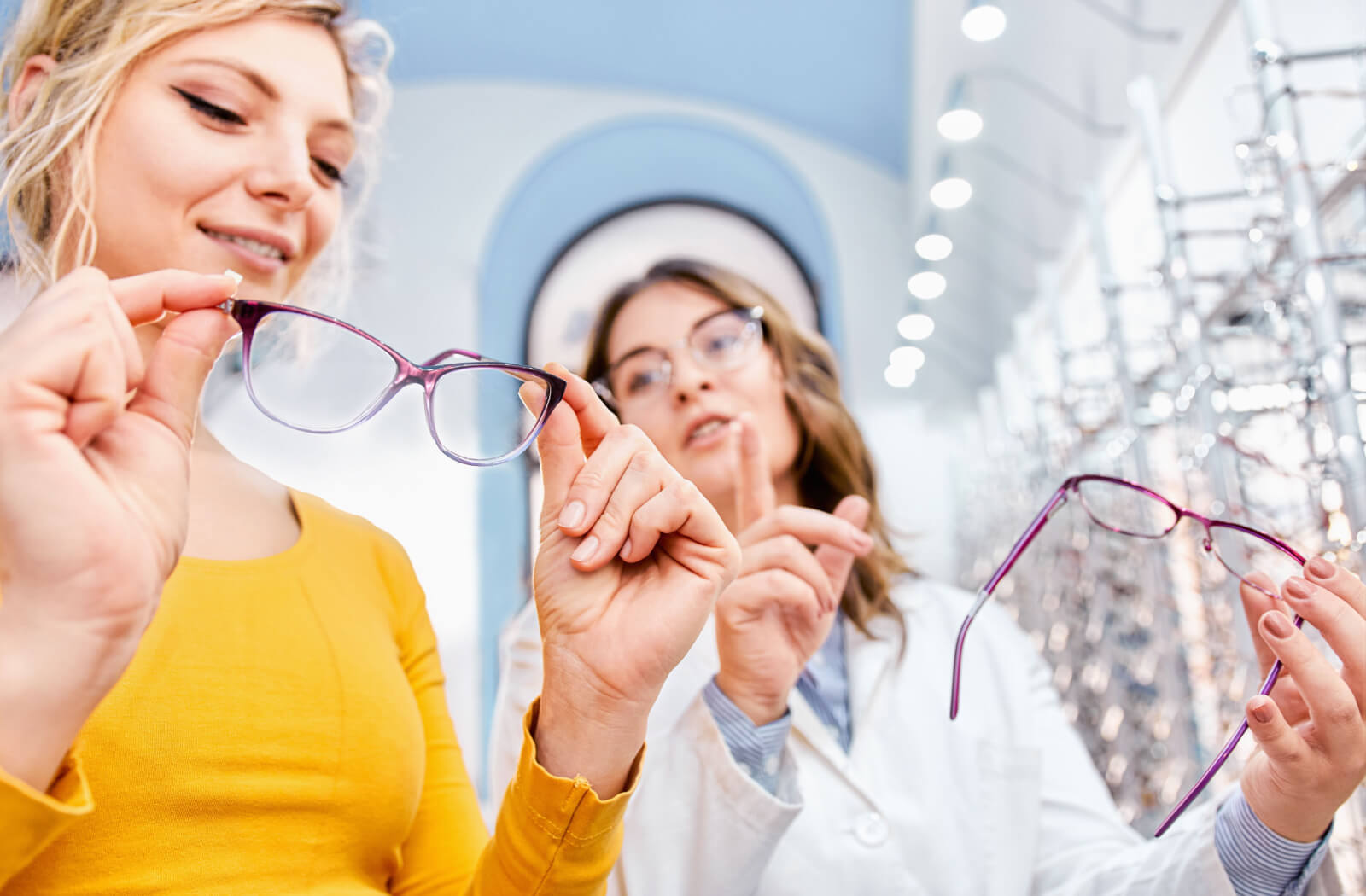 an optometrist and a woman each hold a pair of glasses, showing differences