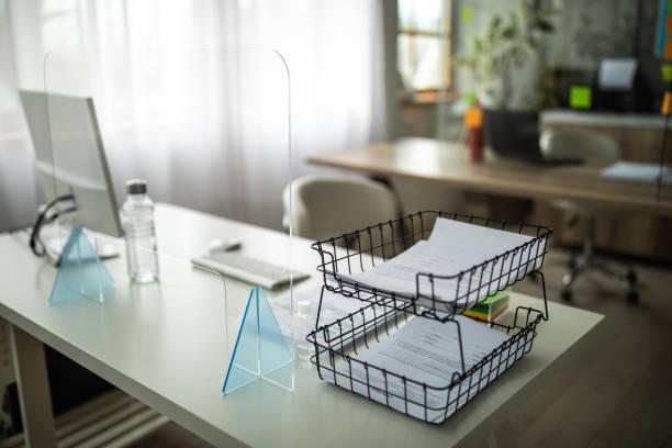 Desk with sneeze guard on it in bank office Desk with sneeze guard, compute monitor and desk organizer with documents on it, in bank office desk organizer stock pictures, royalty-free photos & images