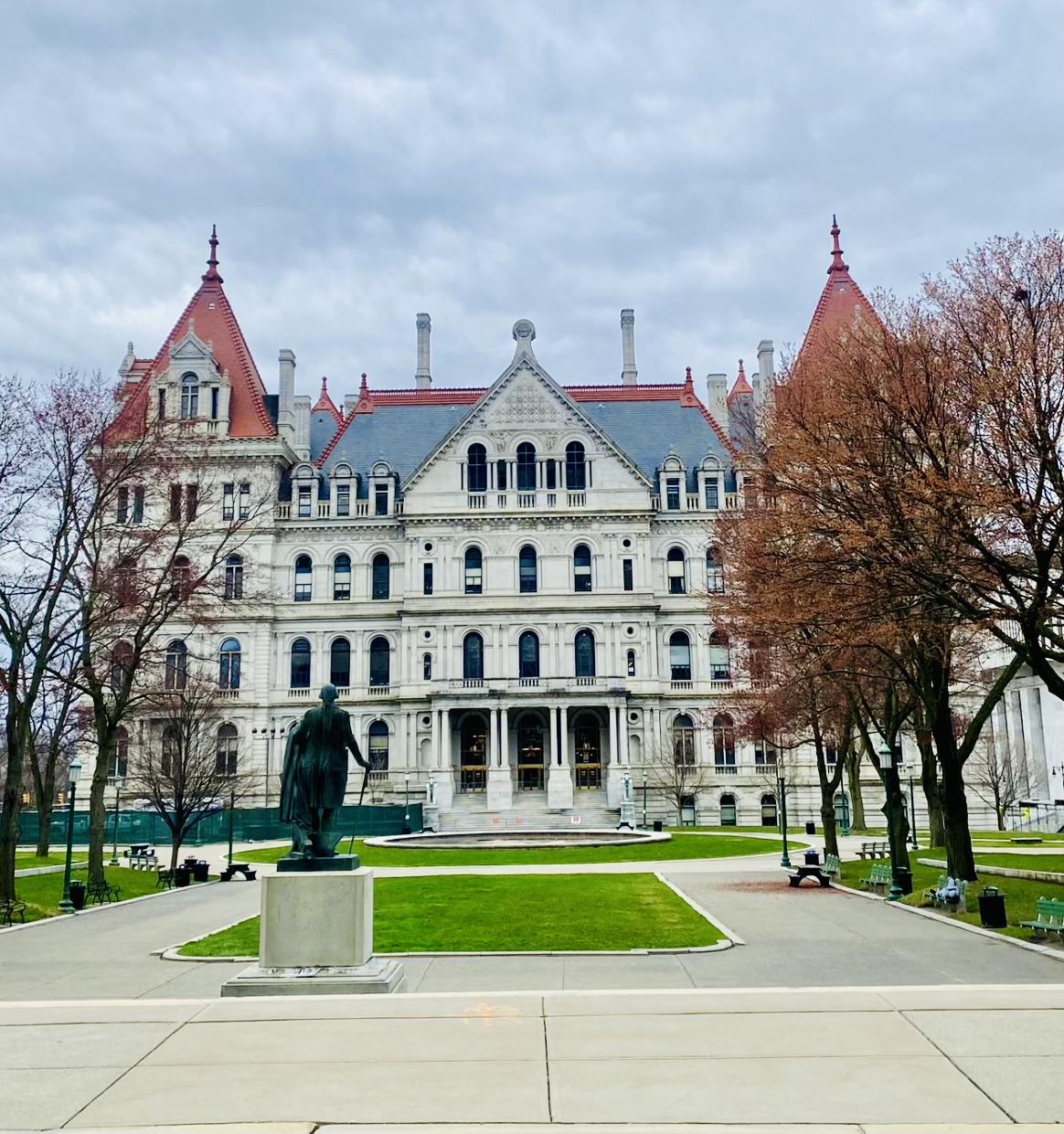 A large white building with a statue in front of it  Description automatically generated