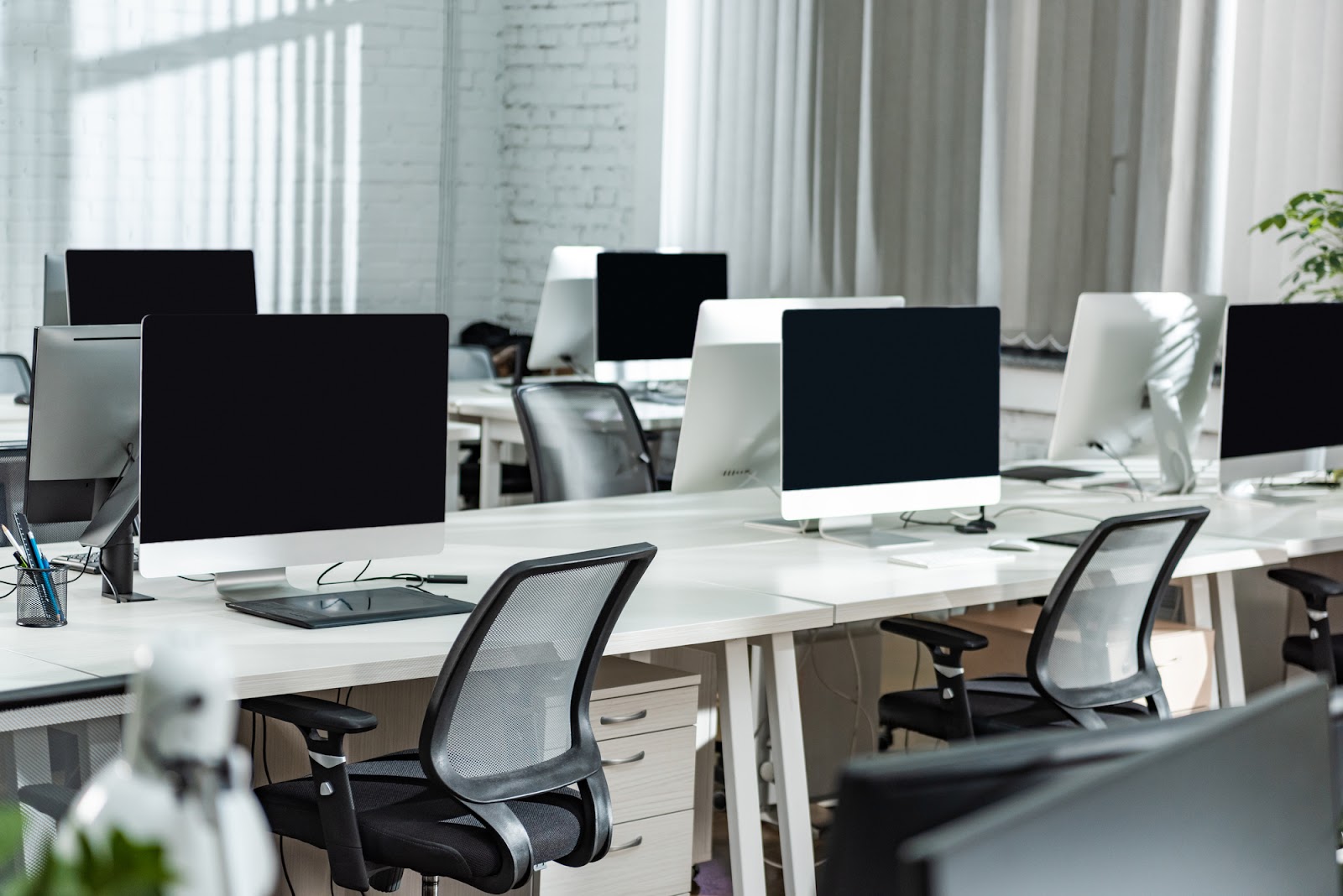 An office workstation with computers, white desks, and ergonomic office chairs